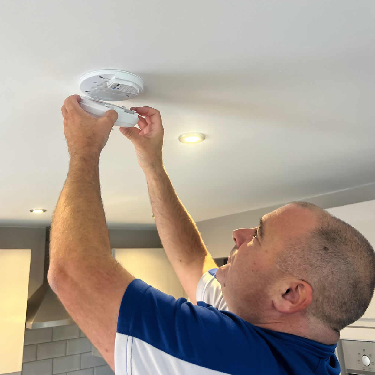 Smoke alarm installer fitting an alarm in a Merthyr Tydfil loft conversion